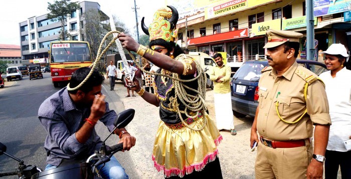 Artist dressed as Yama tying a noose around a biker without helmet Image courtesy: Opennewser